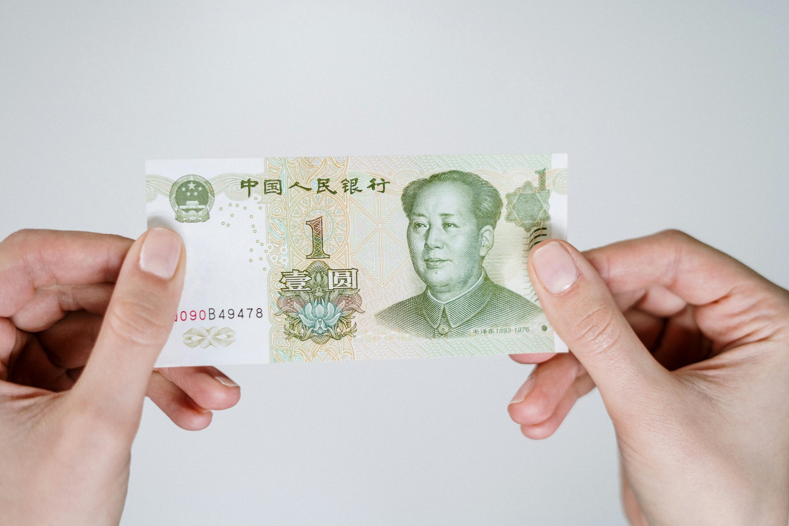 Close-up of hands holding a one Chinese Yuan note, showcasing currency details.
