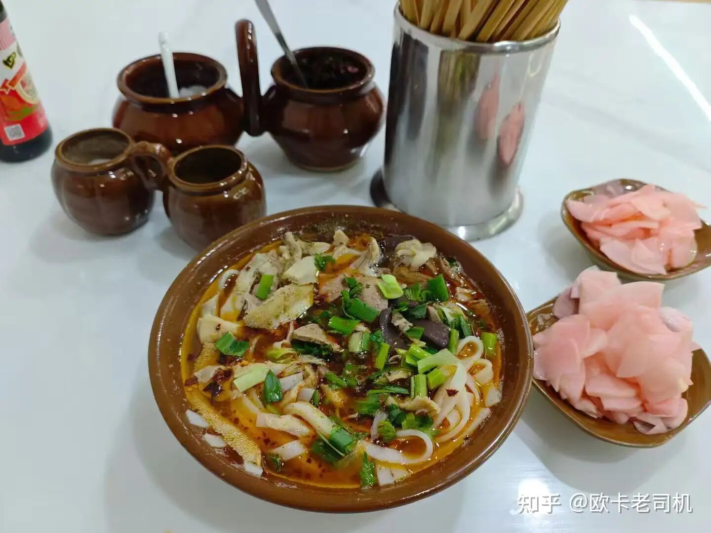 A bowl of regional Chinese rice noodles with chile oil, herbs, and pickled ginger
