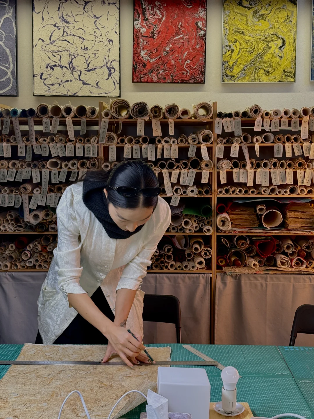A craft worker measures handmade paper in a Beijing hutong-style paper workshop