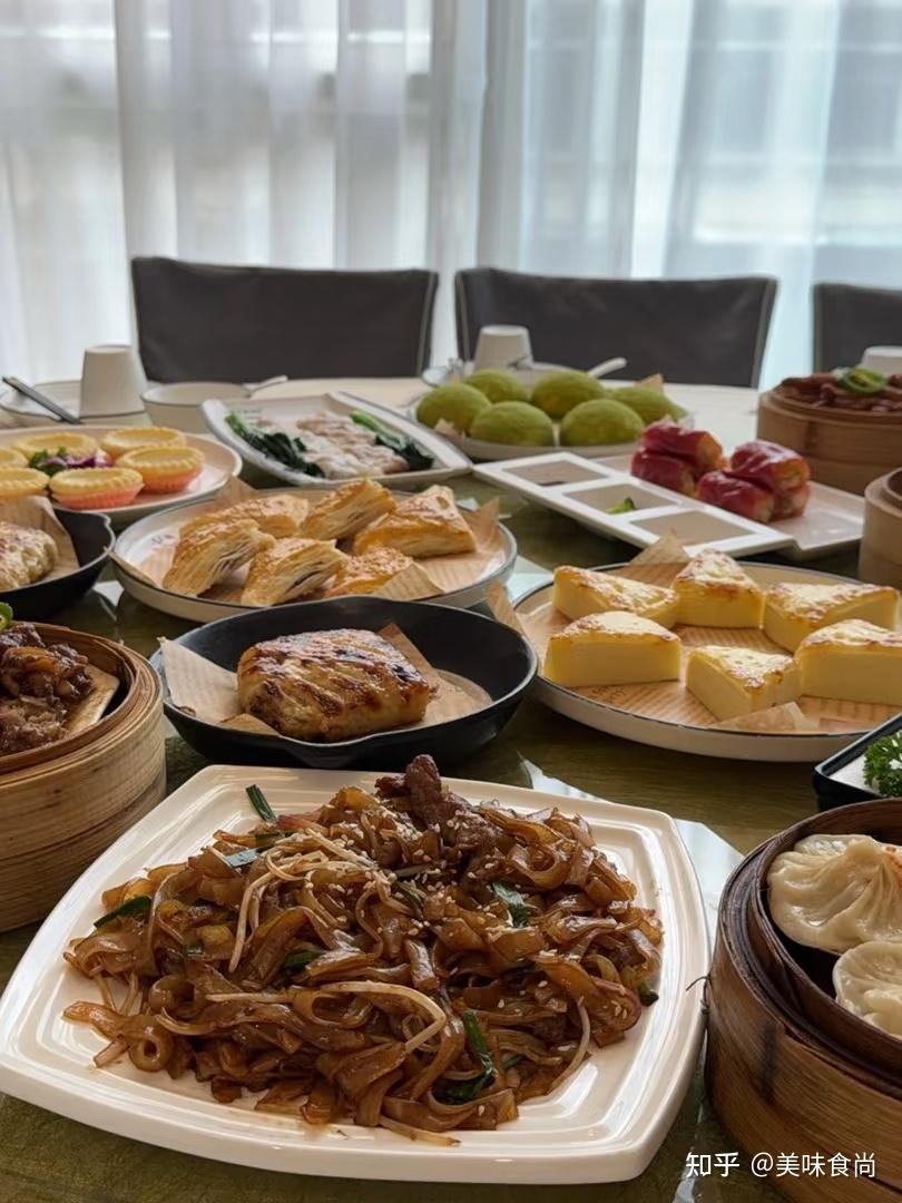 A Guangzhou dim sum table with noodles, tea cups, and shared plates