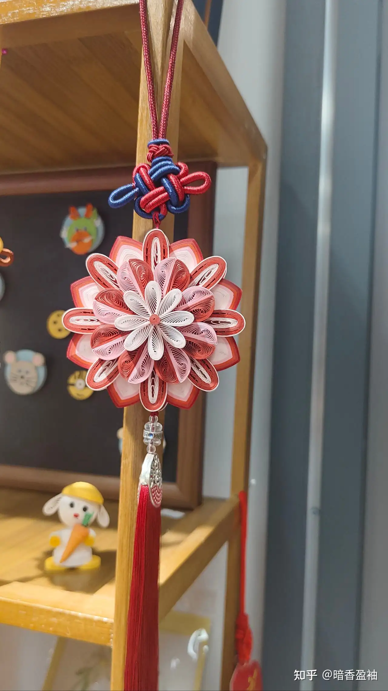 Red and white Chinese knot ornament hanging on a shelf